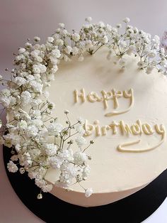 a birthday cake with white flowers and the words happy birthday written on it