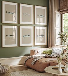 a living room with green walls and pictures on the wall above the couch, along with vases filled with flowers