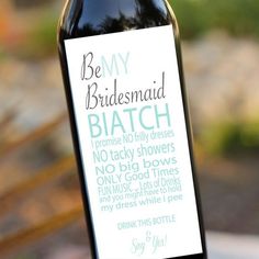 a bottle of wine sitting on top of a table next to a sign that says be my bridesmaid