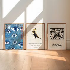 three framed art pieces on the floor in front of a white wall with blue and black artwork