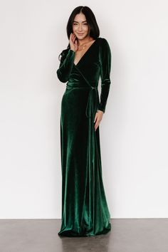 a woman wearing a green velvet dress with long sleeves and a deep v - neck