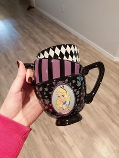 a person holding up a coffee mug with disney characters on it