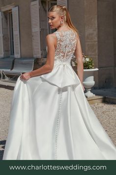 a woman in a white wedding dress is standing on the street with her back to the camera