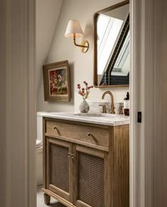 a bathroom with a sink, mirror and pictures hanging on the wall in front of it