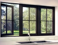 an empty kitchen with black windows and white counter tops