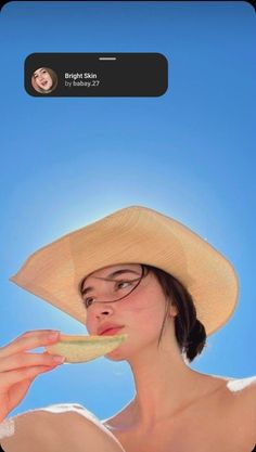 a woman wearing a straw hat eating a piece of food