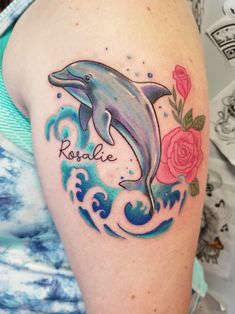 a woman's arm with a dolphin and roses tattoo on the left side of her body