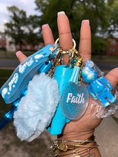 a person's hand holding several key chains and charms in front of them with the word faith on it