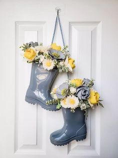 a pair of rubber boots hanging on a door with flowers in them and attached to the handle