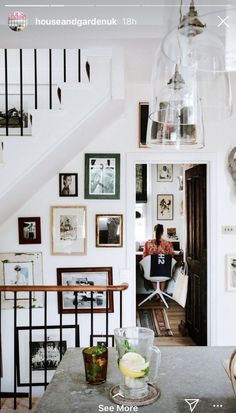 a room with pictures on the wall and a table in front of it, next to stairs