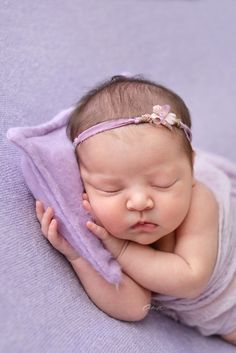 a baby is sleeping on a purple blanket