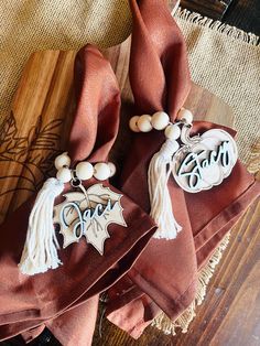 two napkins with tassels on them sitting on top of a wooden table