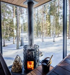 a fire place in the middle of a snow covered forest with logs on the ground