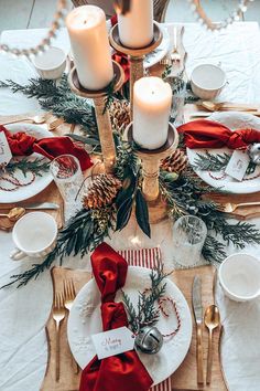 a christmas table setting with candles, plates and napkins