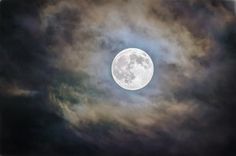 the full moon is seen through clouds in this artistic photo taken on an overcast day