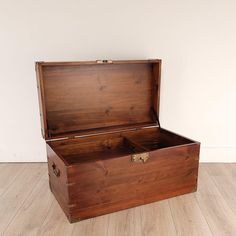 an old wooden trunk sitting on top of a hard wood floor next to a white wall