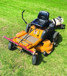 a yellow lawn mower sitting on top of a lush green field