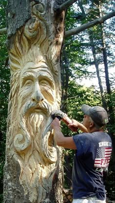 a man is carving a face on a tree