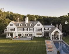 a large white house with a pool in the front yard and lots of lawn furniture