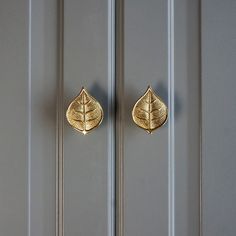 two golden leaves are on the front door handle of a gray painted cabinet with white trim