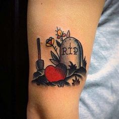 a tattoo on the arm of a person with a grave and flowers in front of it