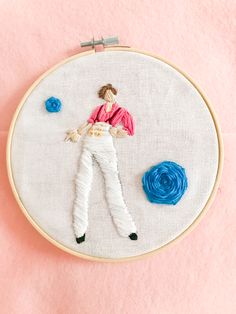 a woman is laying on her stomach in the middle of a embroidery project with blue and pink flowers