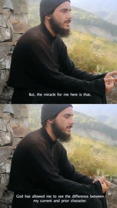 a man with a beard sitting next to a stone wall