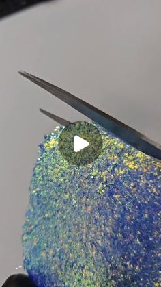 a pair of scissors cutting through a piece of blue and green material with yellow speckles