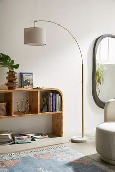 a living room with a chair, lamp and bookshelf on the floor in front of a mirror