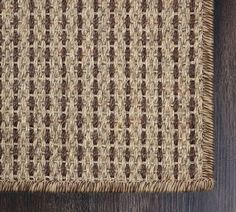 a close up view of a brown and tan rug on a wooden floor with dark wood floors