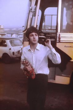 a man standing in front of a bus with his hand on his hip and holding a baseball glove