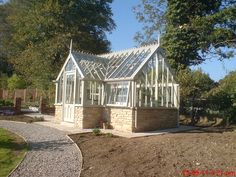 a house that is in the middle of a yard with gravel and trees around it