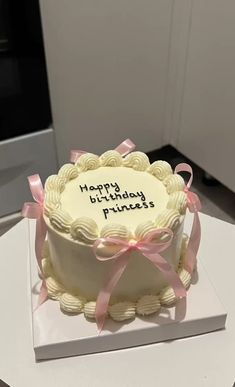 a white cake with pink ribbon and happy birthday princess written on the top is sitting on a table