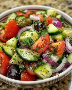 a white bowl filled with cucumber, tomato and onion salad on top of a granite counter