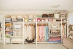 an organized closet with lots of clothes and other items on shelves in the center of the room