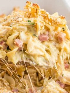 a casserole dish with ham and cheese being lifted from the casserole