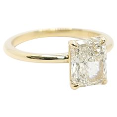 a yellow gold ring with a square cut diamond in the center and a thin band around it