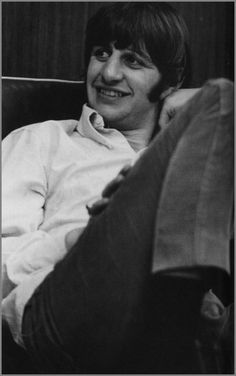 a black and white photo of a person sitting in a chair with his legs crossed