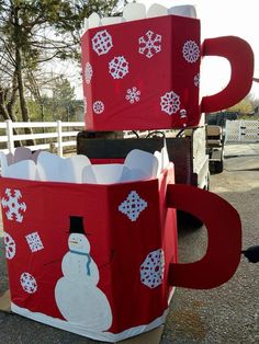 two large red boxes with snowmen on them sitting next to each other in front of a white fence