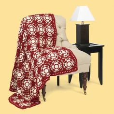 a chair with a blanket on it next to a lamp