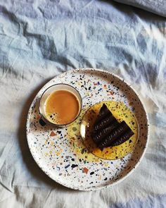 a white plate topped with food next to a cup of coffee on top of a bed