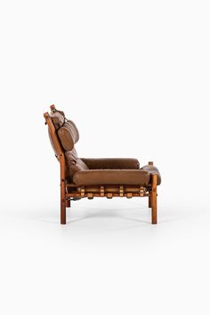 a brown leather reclining chair sitting on top of a white floor next to a wooden frame