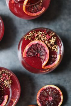 two glasses filled with blood orange juice and garnished with gold flakes