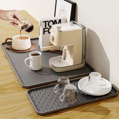 there is a coffee maker and cups on the tray