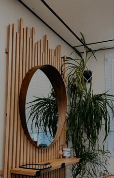 a mirror sitting on top of a wooden shelf next to a potted plant