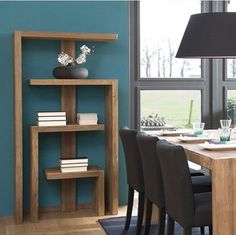 a dining room table with chairs and bookshelf in front of a large window