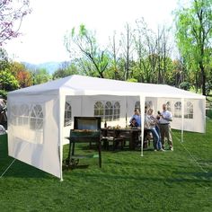 several people standing under a white tent in the grass