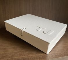 a white box sitting on top of a wooden table next to a wall with the letter u in it