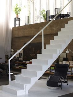 there is a white stair case next to a black chair in the living room area