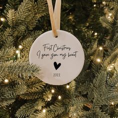 a christmas ornament hanging on a tree with the words, first christmas i give you my heart